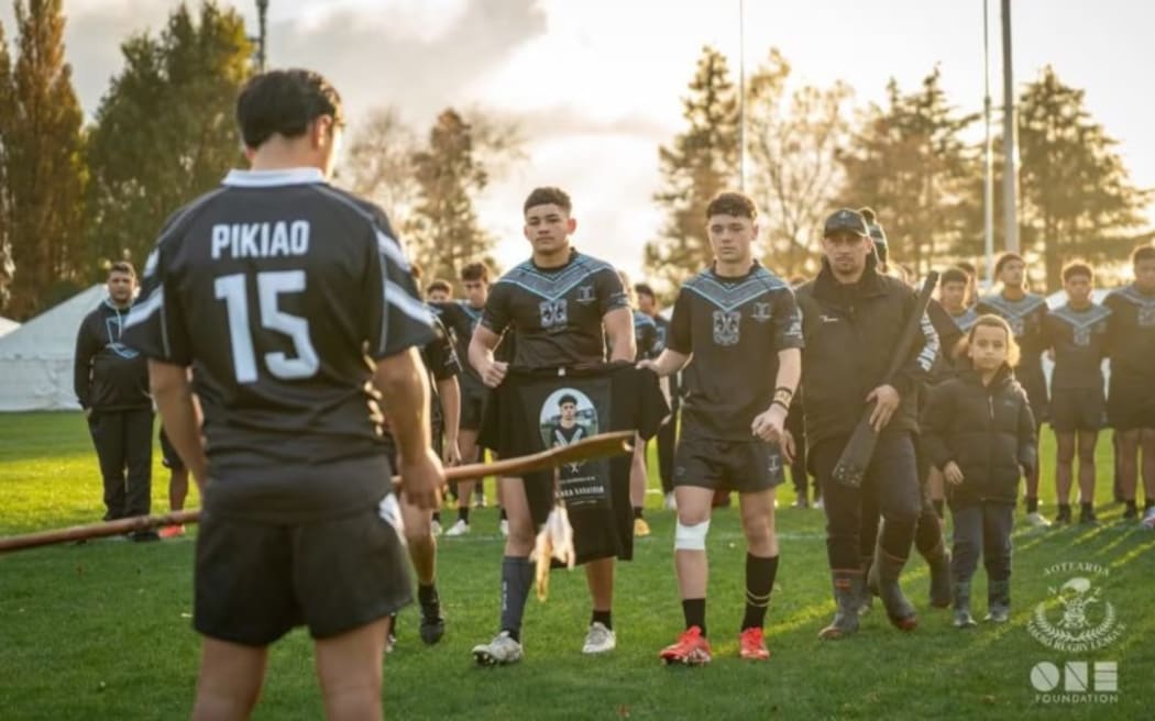 Boys from Kaea Karauria's rugby club hold a tshirt with his picture on it.