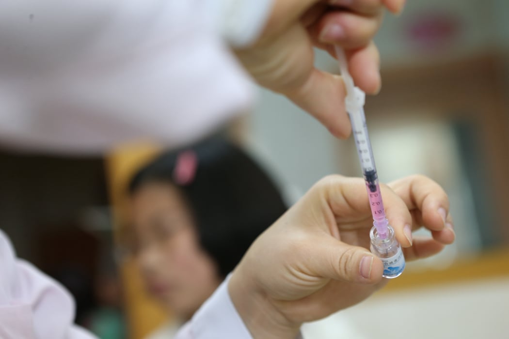 A Chinese medical worker fills up an injector with a dose of vaccine.