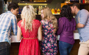Happy friends having a drink together at the bar