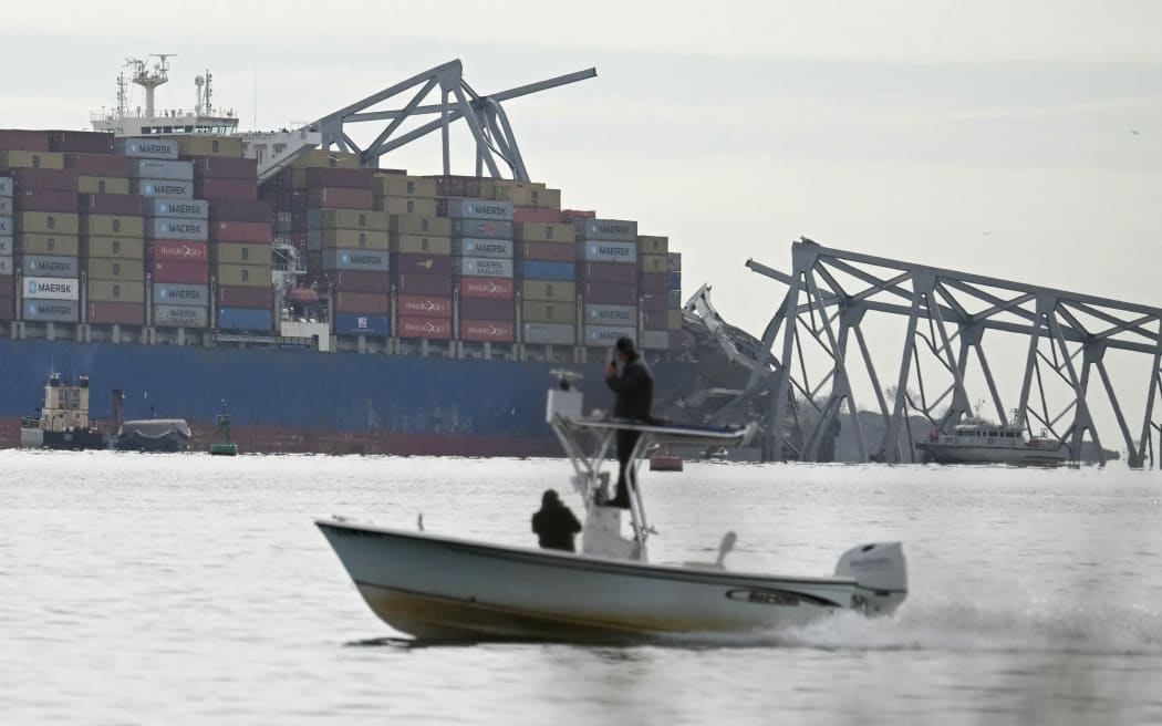 The steel frame of the Francis Scott Key Bridge sits on top of the container ship Dali after the bridge collapsed in Baltimore, Maryland, on March 26, 2024. The bridge collapsed early March 26 after being struck by the Singapore-flagged Dali, sending multiple vehicles and people plunging into the frigid harbor below. There was no immediate confirmation of the cause of the disaster, but Baltimore's Police Commissioner Richard Worley said there was "no indication" of terrorism. (Photo by Mandel NGAN / AFP)