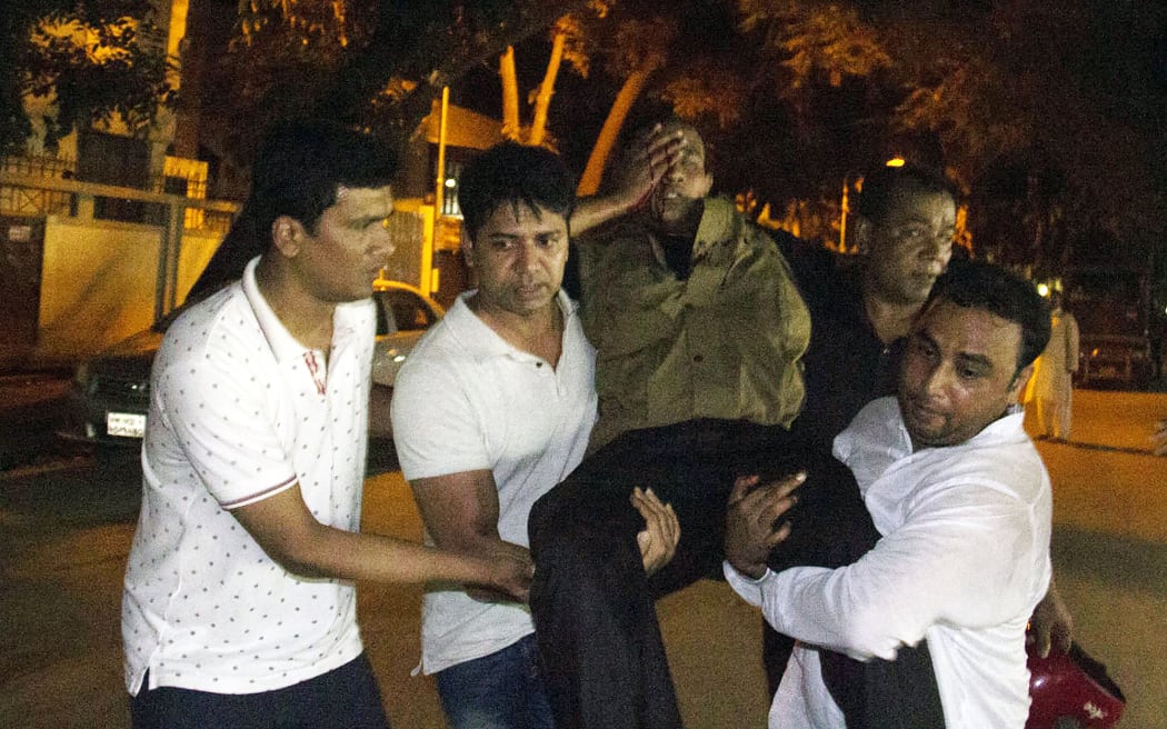 People carry an injured man near the Holey Artisan Bakery