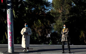 Pedestrians wearing masks and maintaining distance at a traffic light in the Southbank area of Melbourne, 16 July 2021.