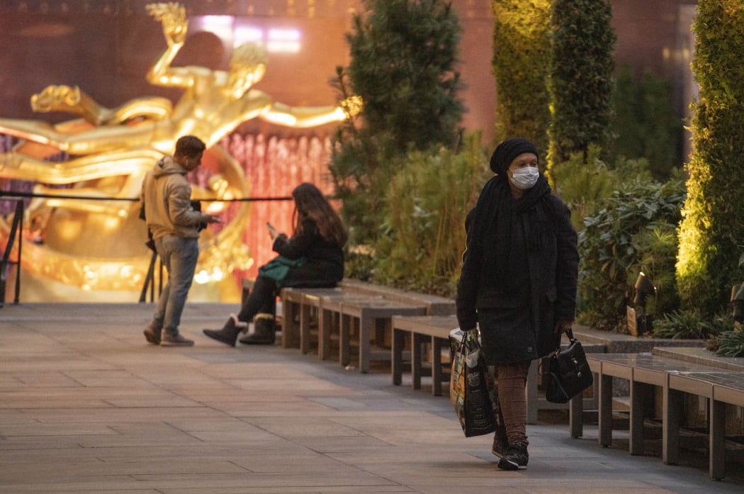 A woman wearing a face mask walks along Rockefeller Center Plaza on Friday, March 2020 in New York, NY.