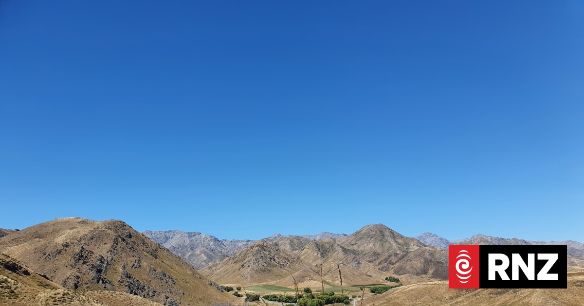Mountain landscape under a clear blue sky with rolling hills.
