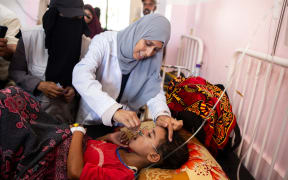 A nurse administers Polio vaccine drops to a young Palestinian patient at the Nasser hospital in Khan Yunis in the southern Gaza Strip on August 31, 2024, amid the ongoing conflict between Israel and the Hamas militant group. The World Health Organization said Israel had agreed to at least three days of "humanitarian pauses" in parts of Gaza, starting on August 31, to facilitate a vaccination drive after the territory recorded its first case of polio in a quarter of a century. (Photo by Jihad Al-Sharafi / AFP)