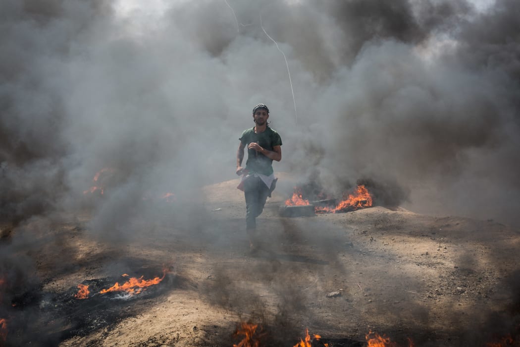A young protester runs away from tear gas thrown by Israeli soldiers in Gaza.
