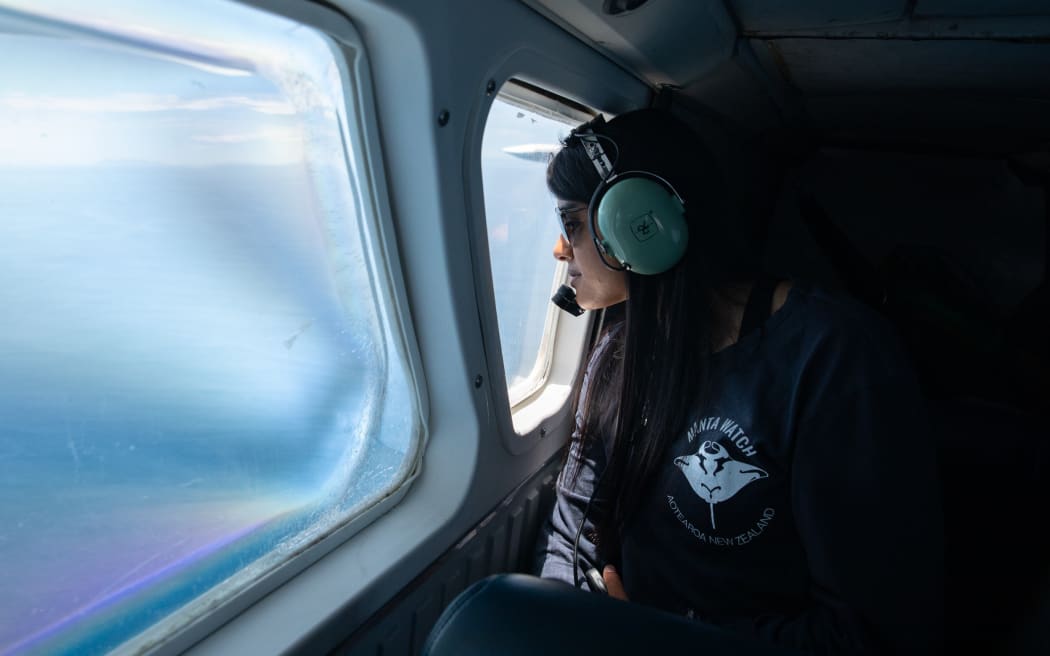 Sanaa Nair, wearing an aviation headset, looks out a plane window