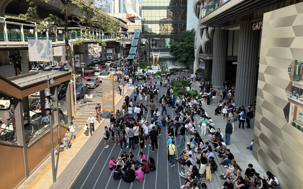People gather outside a shopping mall in Bangkok on March 28, 2025, after an earthquake in central Myanmar. A powerful earthquake rattled Myanmar and neighbouring Thailand on Friday, trapping dozens of workers in a collapsed under-construction skyscraper in Bangkok where a state of emergency was declared. (Photo by Chayanit ITTHIPONGMAETEE / AFP)