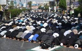 Pakistani Shiite Muslim devotees offer Friday prayers during the procession.