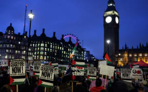 Pro-Palestinian demonstrators wave Palestinian flags and hold placards as they protest in Parliament Square in London during an Opposition Day motion in the the House of Commons calling for an immediate ceasefire in Gaza.