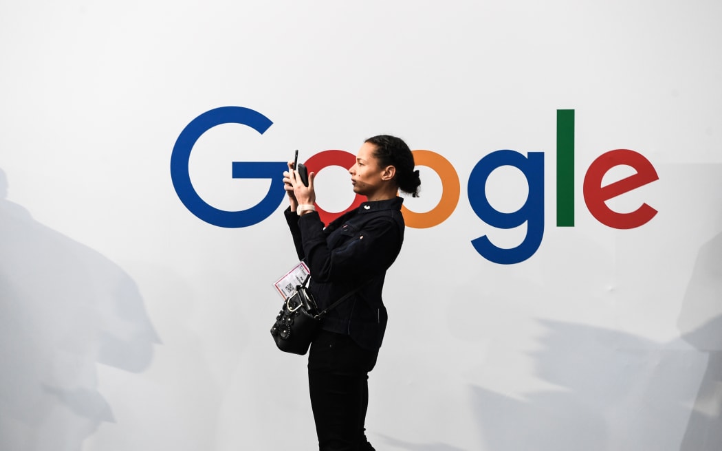 A woman takes a picture with two smartphones in front of the logo of the US multinational technology and Internet-related services company Google as he visits the Vivatech startups and innovation fair, in Paris on May 16, 2019.