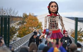 Little Amal, a giant puppet depicting a Syrian refugee girl strides over the Millennium Bridge after a journey across the Clyde with young activists after an earlier appearance at the COP26 UN Climate Change Conference in Glasgow on November 9, 2021. (Photo by Ben STANSALL / AFP)