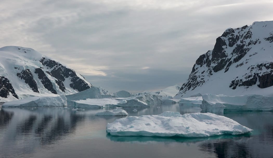 Icebergs. Moving Ice Floes and Ice Sheets in the calm Antarctic Sea, Reflection of Antarctica Mountain in water surface.