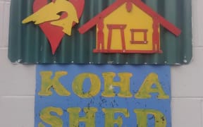 Corrugated iron sign in primary colours saying "Koha Shed"