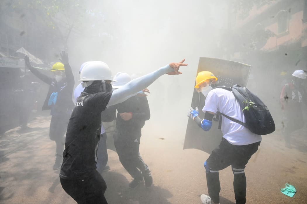 Protesters react after tear gas is fired by police during a demonstration against the military coup in Yangon on March 7.
