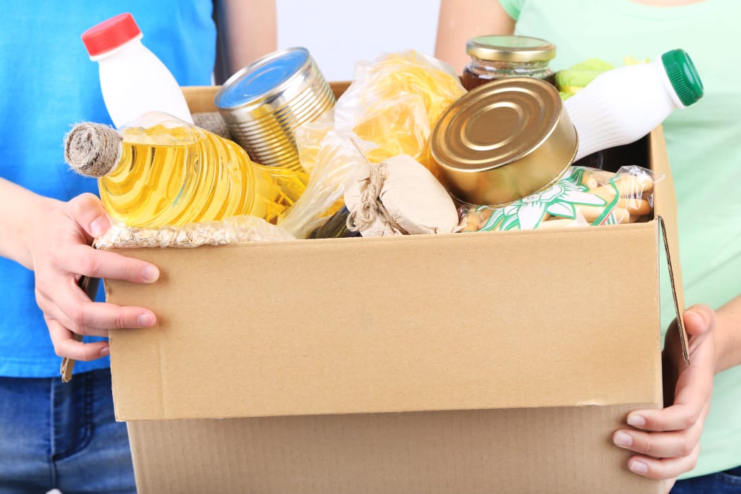 Volunteers with donation box with foodstuffs on grey background - food bank, foodbank