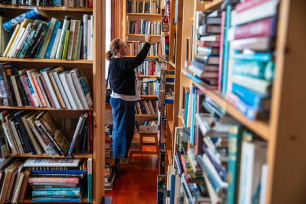 A person reaches for a book on a shelf at Hard to Find Books store, Eden Terrace.