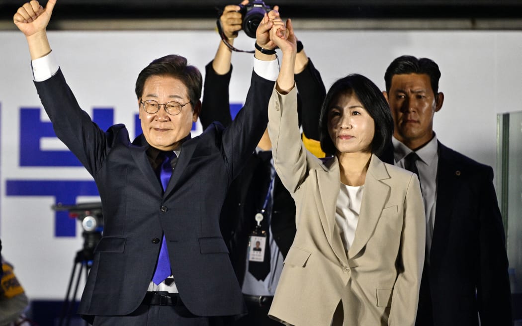 Lee Jae-myung (L) the presidential candidate for South Korea's Democratic Party, and his wife Kim Hye-gyeong (R) acknowledge supporters as they await the final results of the presidential election in Seoul on June 4, 2025. (Photo by ANTHONY WALLACE / AFP)