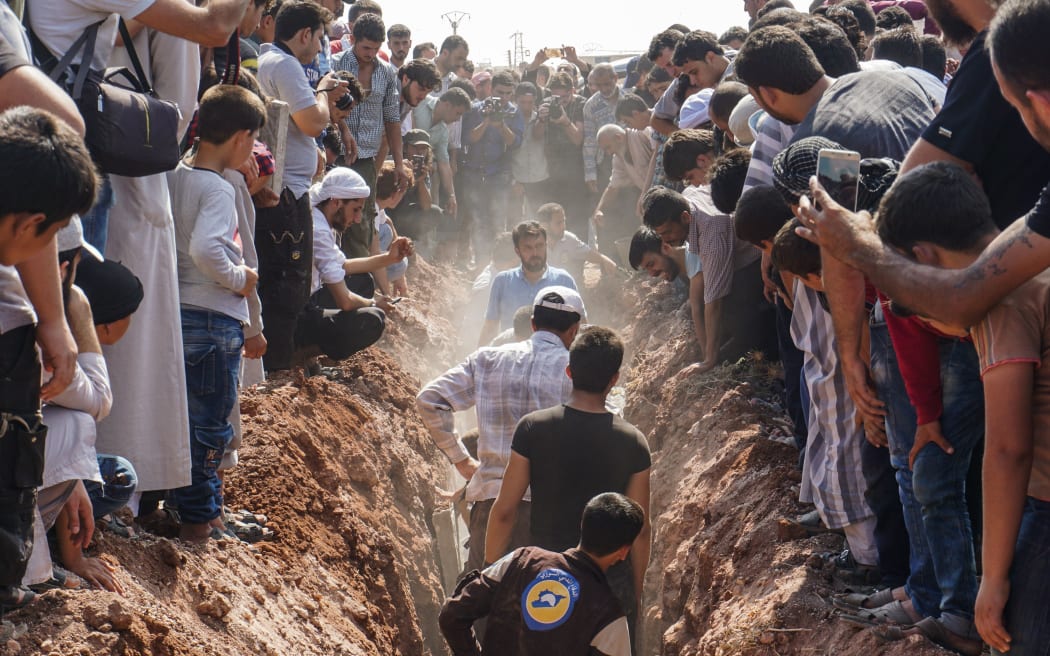 Members of the White Helmets bury their fellow comrades, murdered at a base in the province of Idlib.