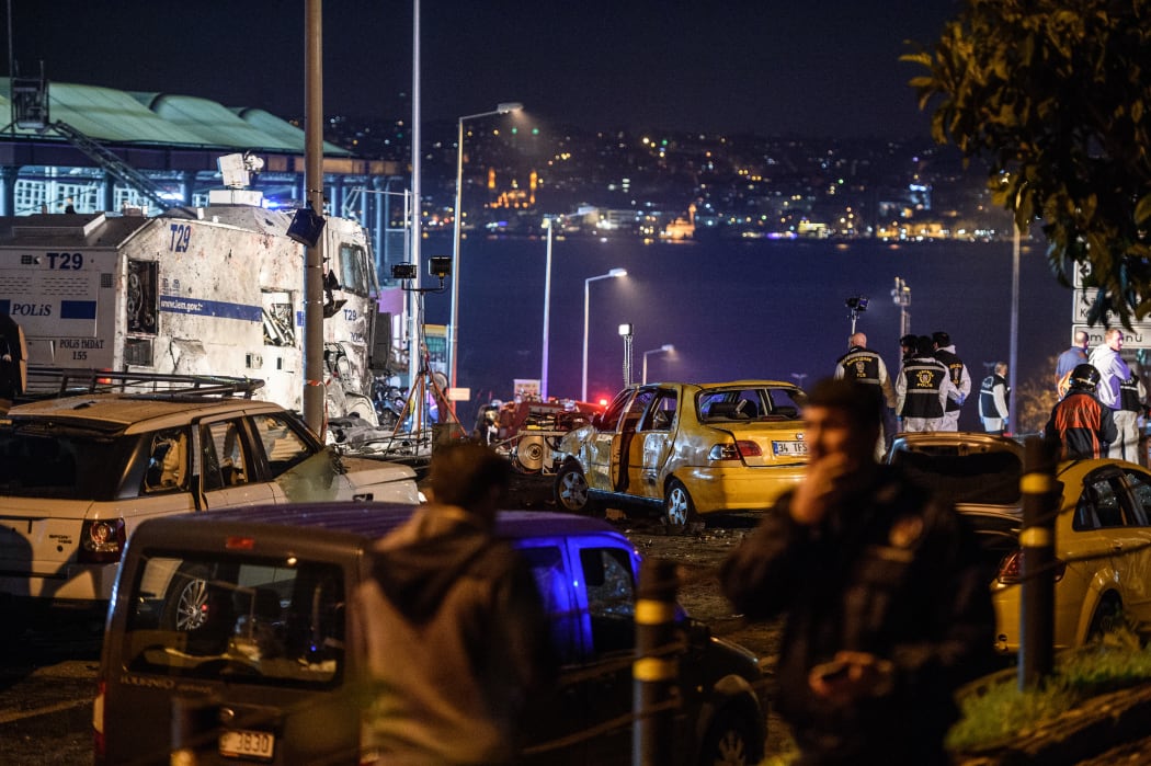 Turkish police officers and forensic work next to damaged police vehicles and cars on the site where a car bomb exploded near the stadium of football club Besiktas in central Istanbul on December 10, 2016.