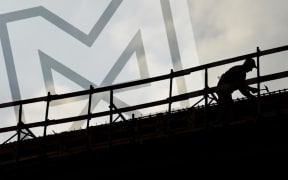 construction worker silhouette on a construction with coudy sky on background