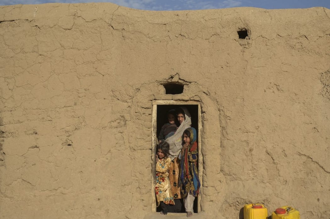 An Afghan family stands by the door of their home in the village Haji Rashid Khan in Badghis province where climate change is proving a deadlier foe than the country's recent conflicts.