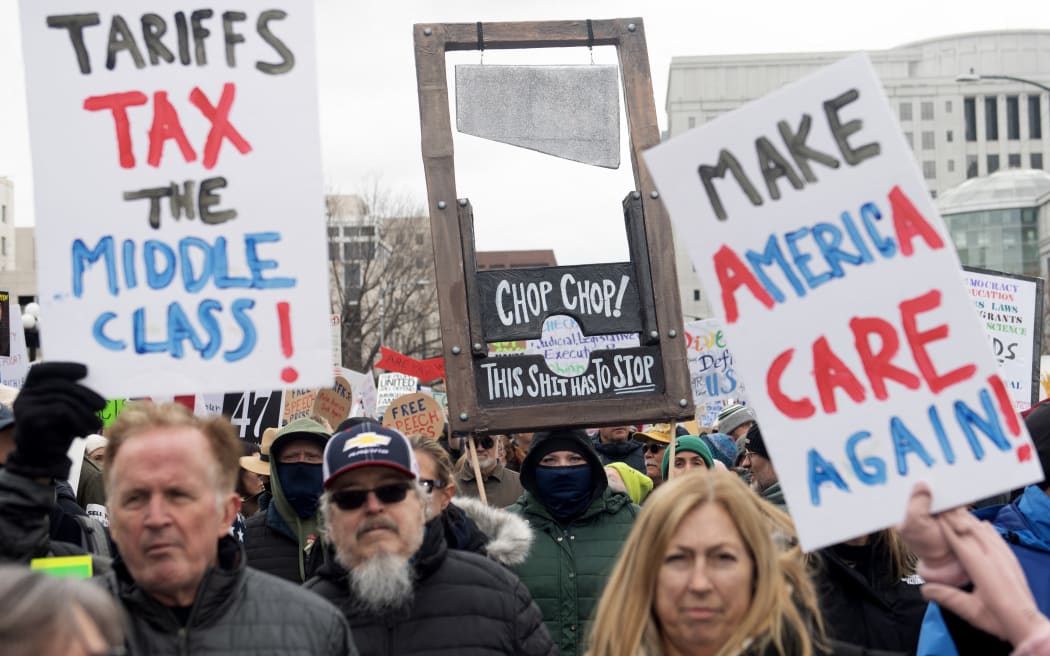 Demonstrators hold up signs during the nationwide “Hands Off” protest against US President Donald Trump and his advisor, Tesla CEO Elon Musk, at the Colorado Capital in Denver, Colorado on April 5, 2025. Protesters flooded the streets of several major US cities on Saturday to oppose the divisive policies of President Donald Trump, in the largest demonstrations since his return to the White, House. Opponents of the Republican president's policies -- from government staffing cuts to trade tariffs and eroding civil liberties -- rallied in Washington, New York, Houston, Los Angeles and Florida, among other locations. (Photo by Jason Connolly / AFP)