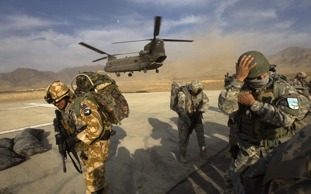 US Army soldiers from 2-506 Infantry 101st Airborne Division, Afghan National Army soldiers and a New Zealand Army soldier take cover as a CH-47 Chinook helicopter lands to transport them on day one of Operation Radu Bark VI into the Spira mountains in Khost province, five kms from the Afghan-Pakistan Border, directly across the border from Pakistan's lawless Waziristan region on November 11, 2008.  US soldiers along with the Afghan National Army launched Operation Radu Bark VI in the Spira mountains setting up a patrol base along a known insurgent infiltration route, at altitudes up to 10,000 feet, conducting dismounted maneuvers in the mountains, and setting up observation posts throughout the area.  AFP PHOTO/DAVID FURST (Photo by DAVID FURST / AFP)