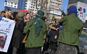 Taliban fighters trying to control women as they chant slogans during a protest demanding for equal rights, along a road in Kabul on 16 December, 2021.