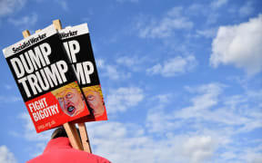 A demonstrator holds placards during a protest outside Buckingham Palace against US President Donald Trump's visit.