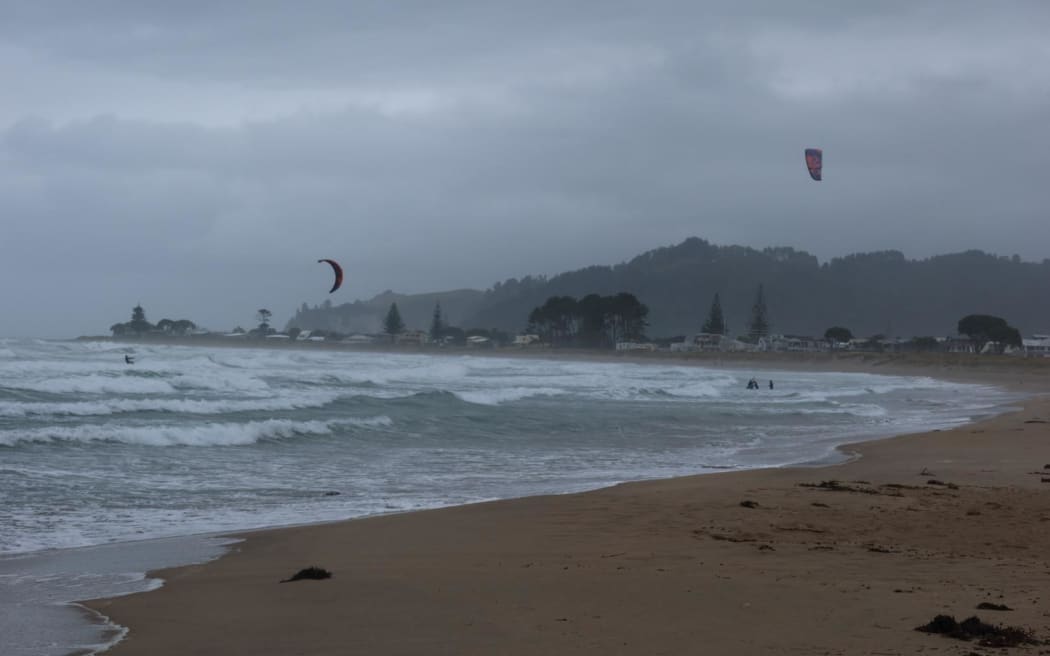 Kite-surfers out in driving rain and wild winds.