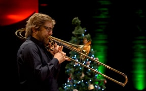 David Bremner playing trombone in front of a Christmas tree