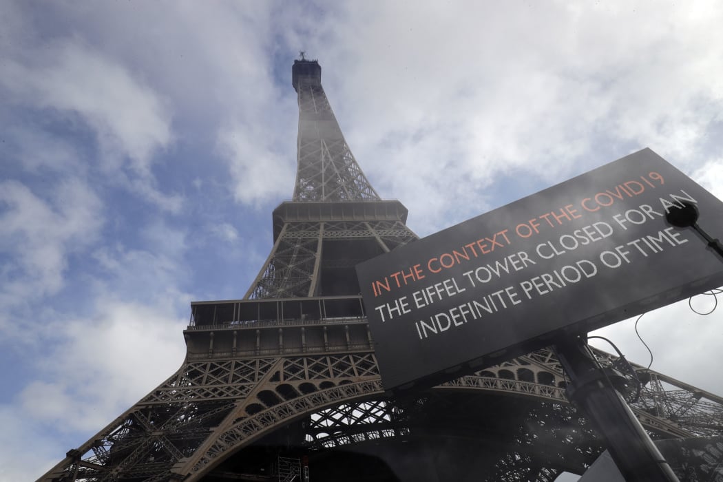 A picture taken on March 14, 2020 near the Eiffel tower in Paris shows a board informing of the monument's closure as a precaution against the coronavirus.