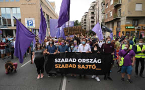 Activists and sympathizers of the centrist Hungarian political party 'Momentum Movement' hold a banner which reads "Free country, free press" as they march on the street beside the editorial building of 'Index'