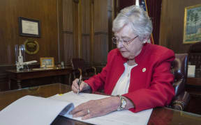 Alabama Governor Kay Ivey signing a bill that virtually outlaws abortion in the state.