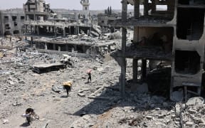 Palestinians transport salvaged items past destroyed buildings in the al-Tuffah neighbourhood of Gaza City on August 14, 2025, following more than 22 months of war between Israel and the Palestinian militant group Hamas. The Israeli military said on August 13, that it had approved the framework for a new offensive in the Gaza Strip, as Hamas condemned what it called "aggressive" Israeli ground incursions in Gaza City. The approved plan for the expanded offensive comes days after Israel's security cabinet called for the capture of the Palestinian territory's largest city following 22 months of war that have created dire humanitarian conditions. (Photo by Omar AL-QATTAA / AFP)