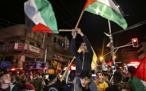 Palestinians and supporters of the Islamic Jihad militant group celebrate in the street after Palestinian factions and Israel reached a ceasefire agreement in Gaza City on May 13, 2023.