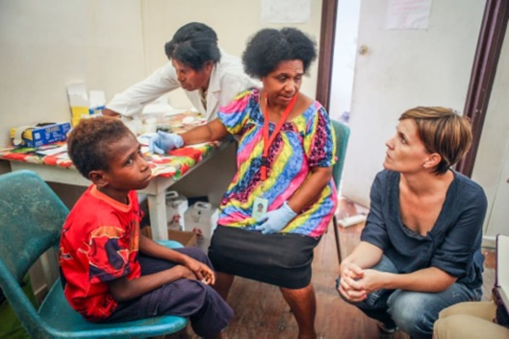 Dr Leanne Robinson (far right) with patient Jonathan (far left), who is being tested for malaria by Nursing Officer Kay Kose (second from left) and microscopist Barbara Sambre (second from right).