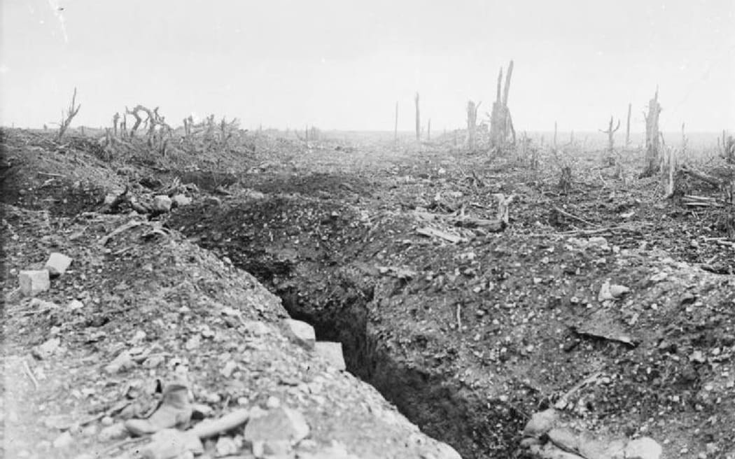 The badly shelled main road to Bapaume through Pozieres, showing a communication trench and broken trees.