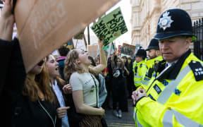 Police watch students in the London as they protest over climate change.