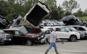 A worker walks past tornado-damaged cars at a dealership in Jefferson City, Missouri.