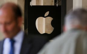 People wait outside the Apple store in Covent Garden in London.