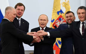 (L-R) The Moscow-appointed heads of Kherson region Vladimir Saldo and Zaporizhzhia region Yevgeny Balitsky, Russian President Vladimir Putin, Donetsk separatist leader Denis Pushilin and Lugansk separatist leader Leonid Pasechnik join hands after signing treaties formally annexing four regions of Ukraine Russian troops occupy, at the Kremlin in Moscow on September 30, 2022. (Photo by Grigory SYSOYEV / SPUTNIK / AFP)