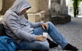 A homeless man begging on the street.