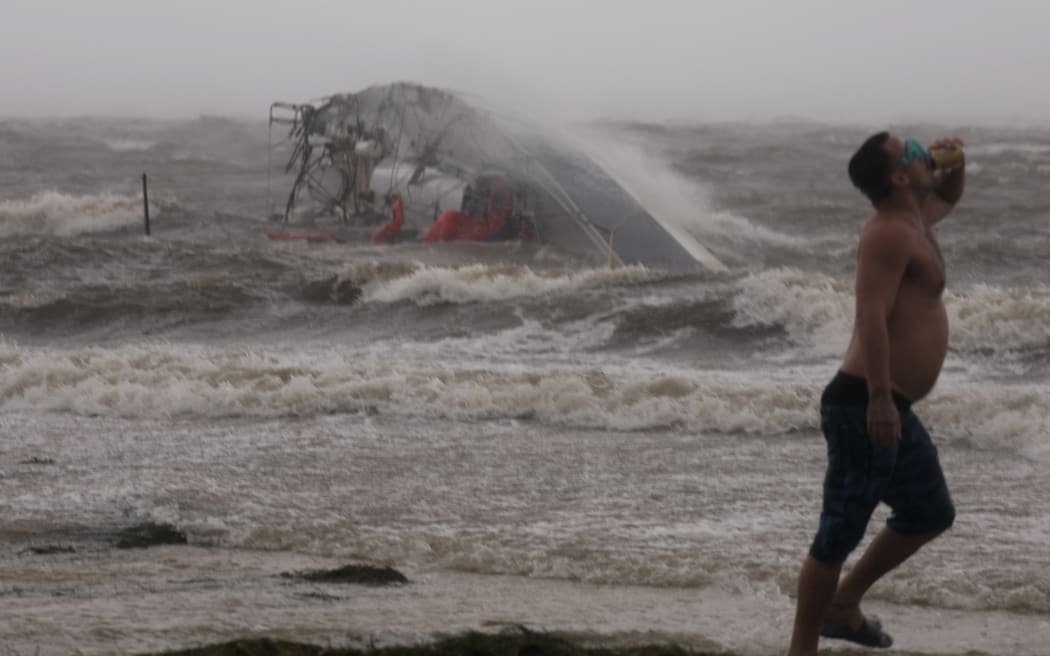 Nick Ward wears goggles to protect his eyes against the wind as he walks past a capsized boat being washed against the ashore, in St. Petersburg Florida, before Hurricane Helene has hit land, on 26 September, 2024.