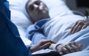 Young woman in hospice care, holding hands in hospital.
