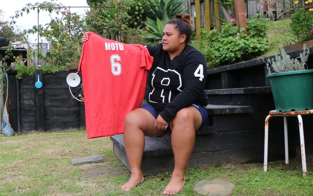 Woman sits on step in her garden holding her red kabbadi shirt