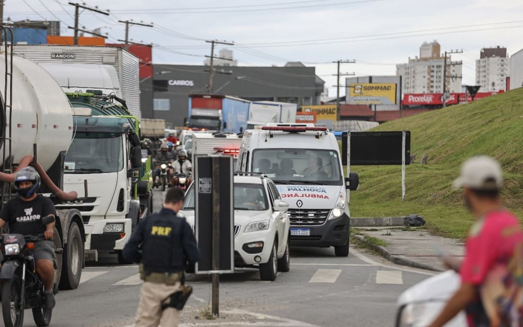 Supporters of President Jair Bolsonaro, mainly truck drivers, block BR-101 highway in Palhoca, in the metropolitan region of Florianopolis, Santa Catarina State, Brazil, on October 31, 2022, as an apparent protest over Bolsonaro's defeat in the presidential run-off election. - The transition period got off to a tense start as truckers and demonstrators blocked several highways across Brazil on Monday in an apparent protest over the electoral defeat of Bolsonaro to leftist Luiz Inacio Lula da Silva, burning tyres and parking vehicles in the middle of the road to halt traffic. (Photo by Anderson COELHO / AFP)
