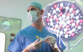 Orthopaedic surgeon in operating theatre with replacement hip stem. (File photo)