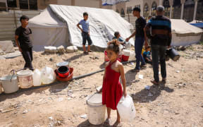 A girl holds plastic containers as displaced Palestinians collect water at a camp in Gaza City, on 20 May 2025, amid the ongoing war between Israel and the Palestinian militant movement Hamas.